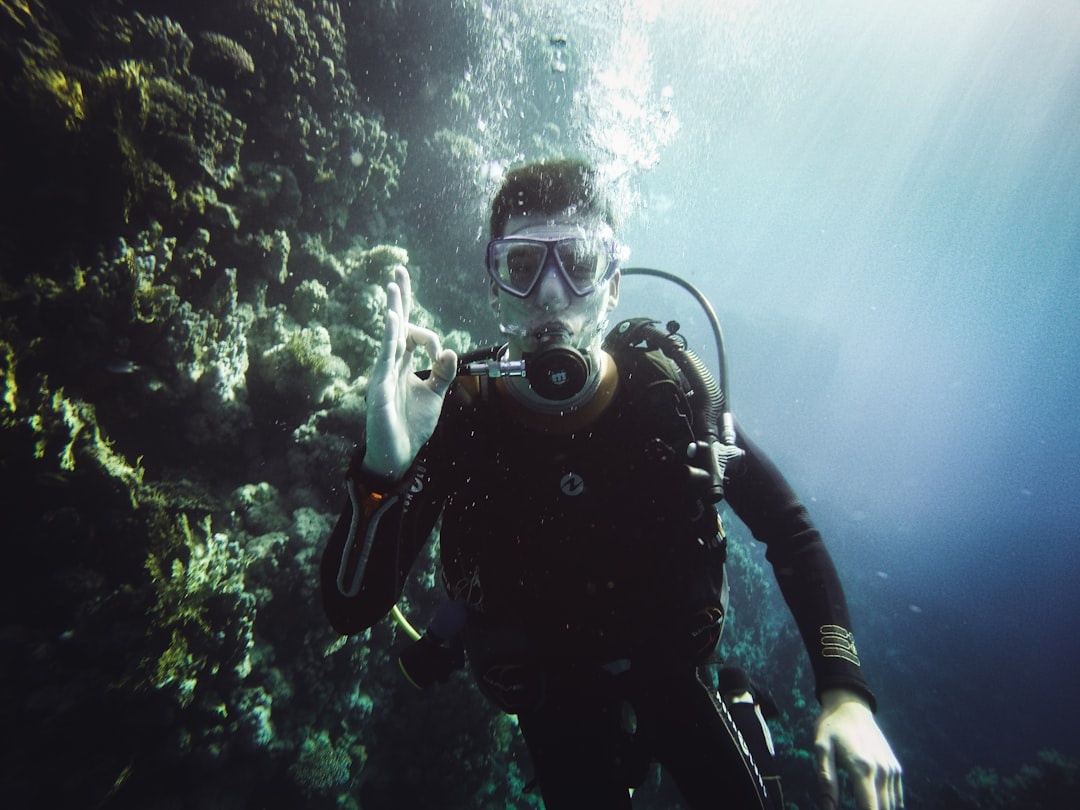 Scuba diver giving the OK sign next to a Red Sea reef wall